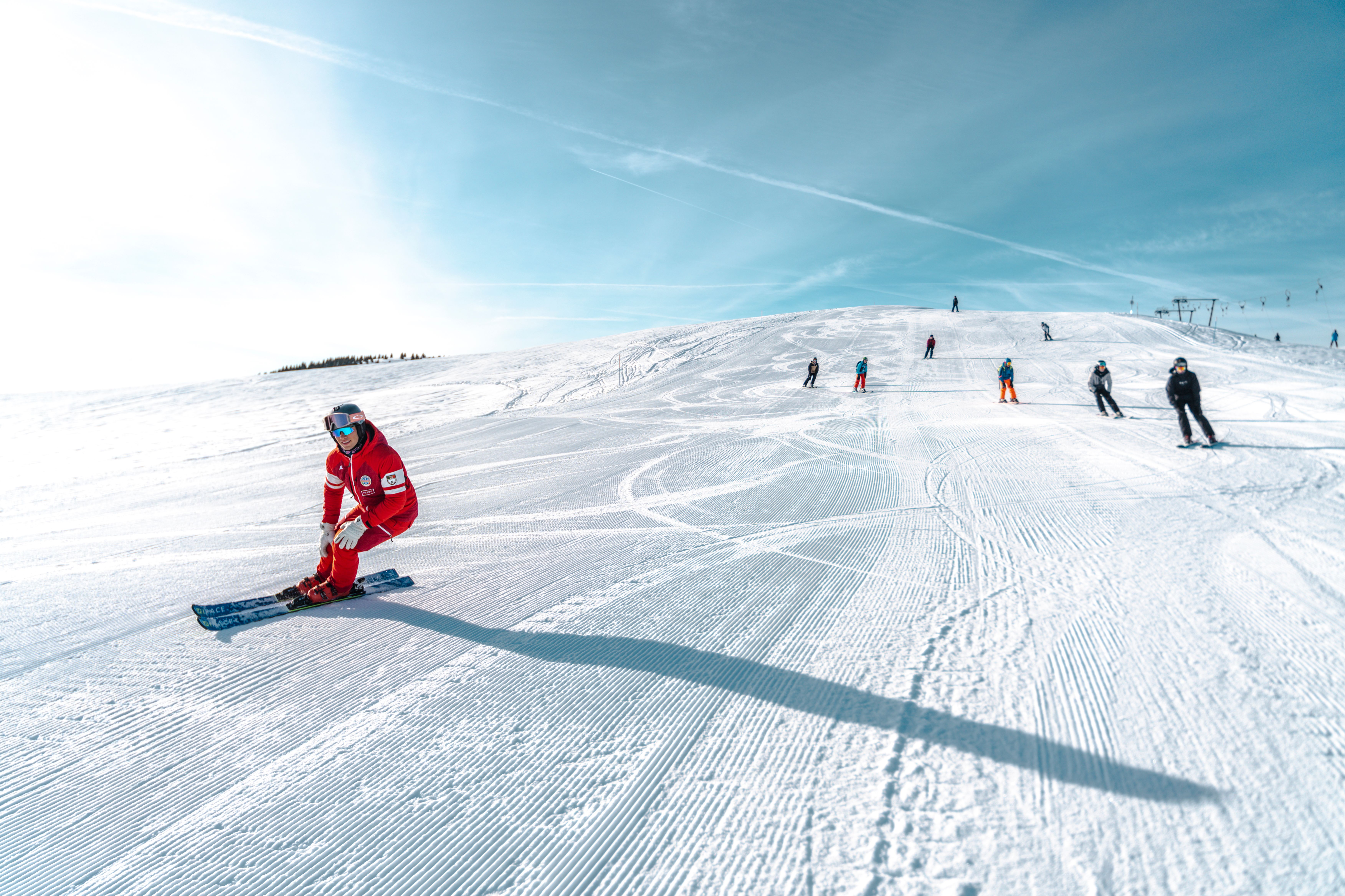 Skiers on a groomed run under blue sky